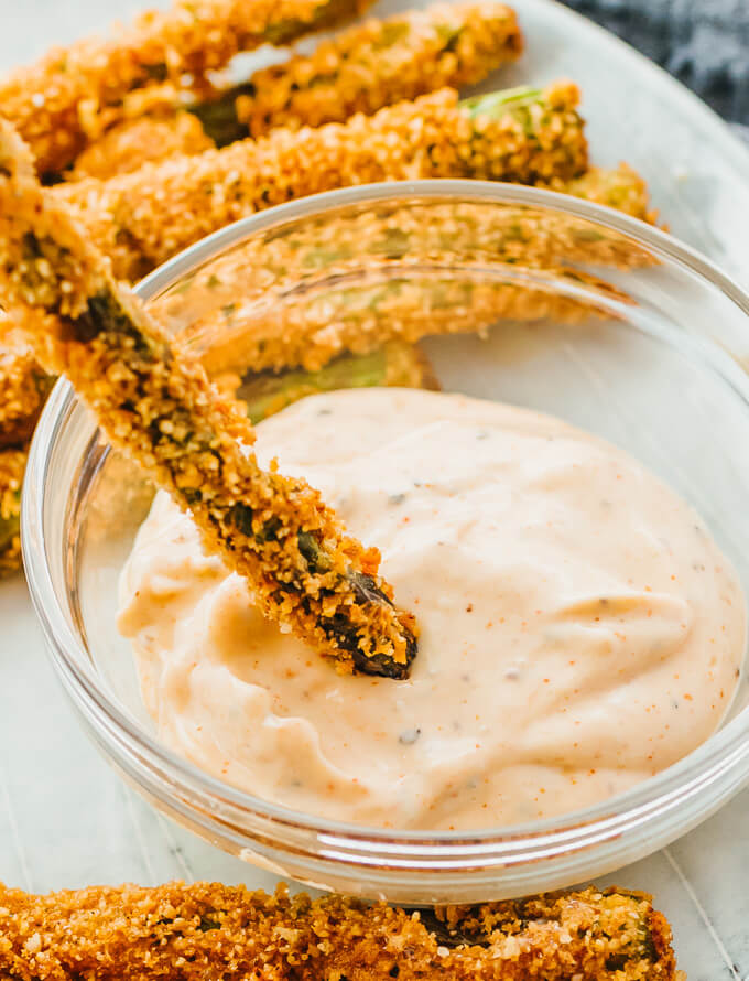 dipping fried asparagus spear into spicy mayo