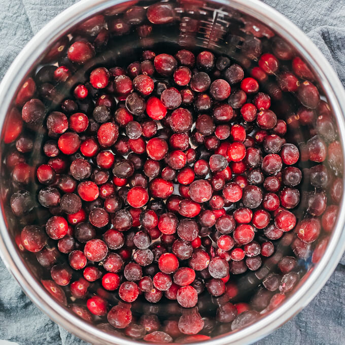 adding cranberries to pressure cooker pot to make homemade cranberry sauce
