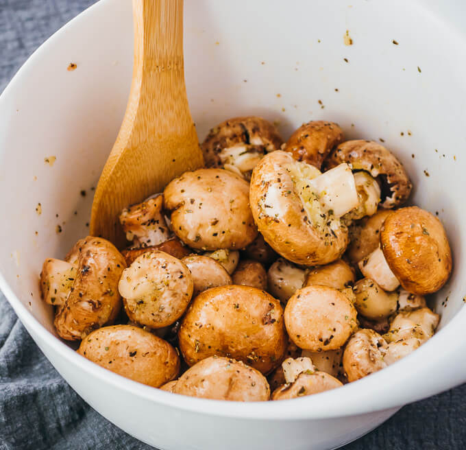 mixing mushrooms with seasonings and oil