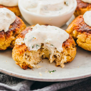 close up view of salmon patties with sour cream dip