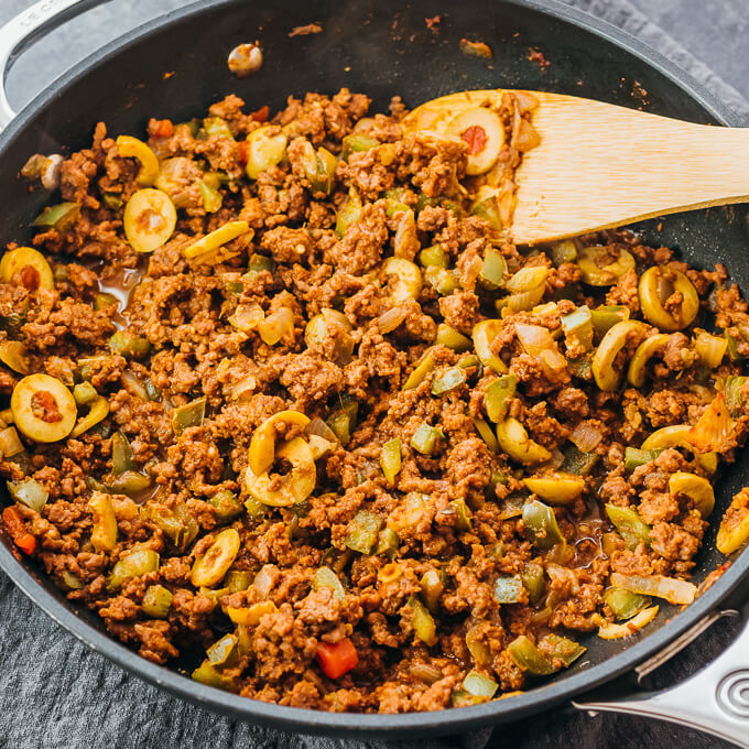 stirring ground beef picadillo in skillet