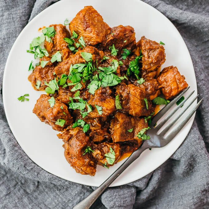 boneless pork butt with savory sauce on a white plate