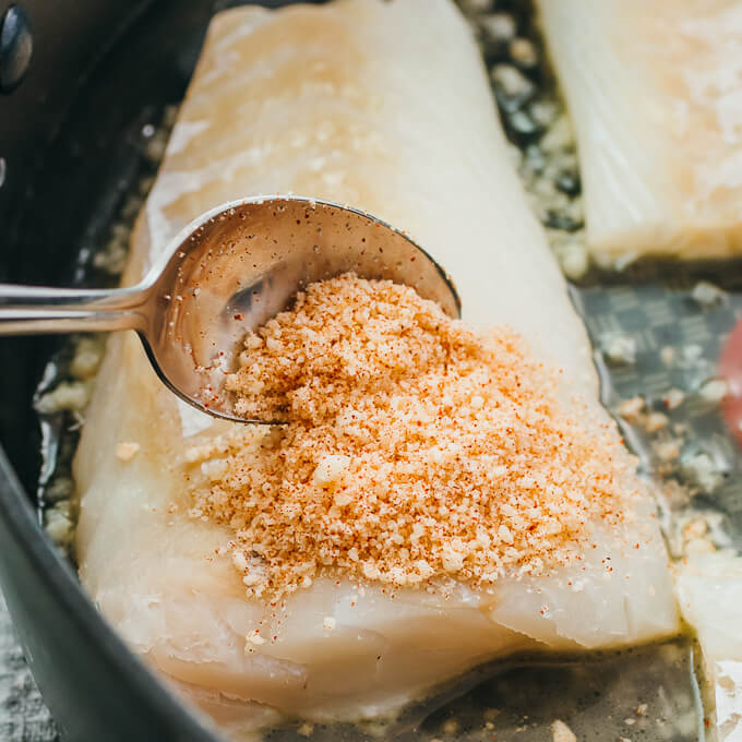 spooning parmesan topping over the fillets