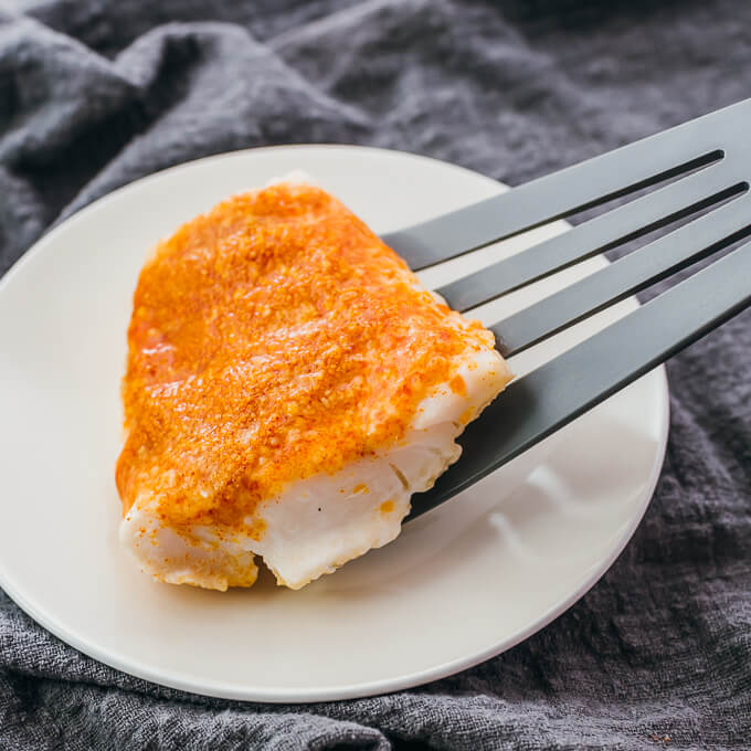 serving baked cod onto a plate