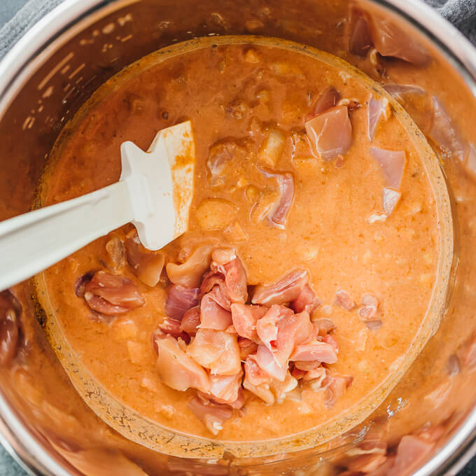 stirring chicken thighs and curry ingredients in pot