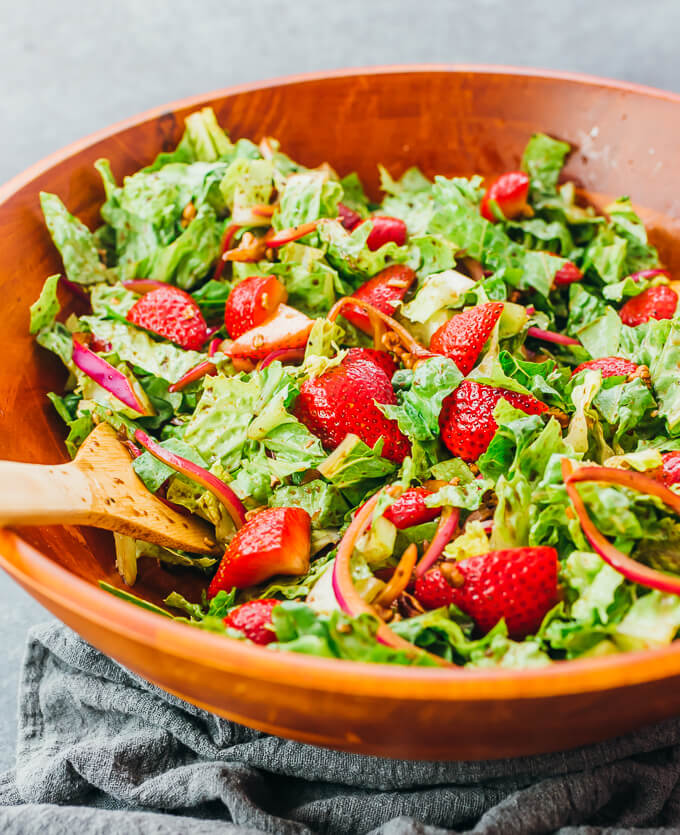 mixing strawberry salad with balsamic dressing