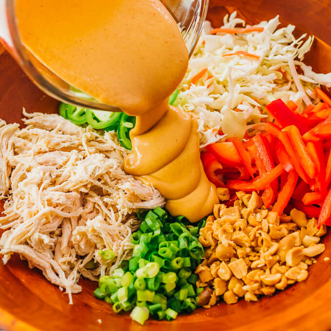 pouring peanut sauce over thai salad