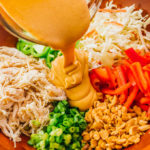 pouring peanut sauce over thai salad