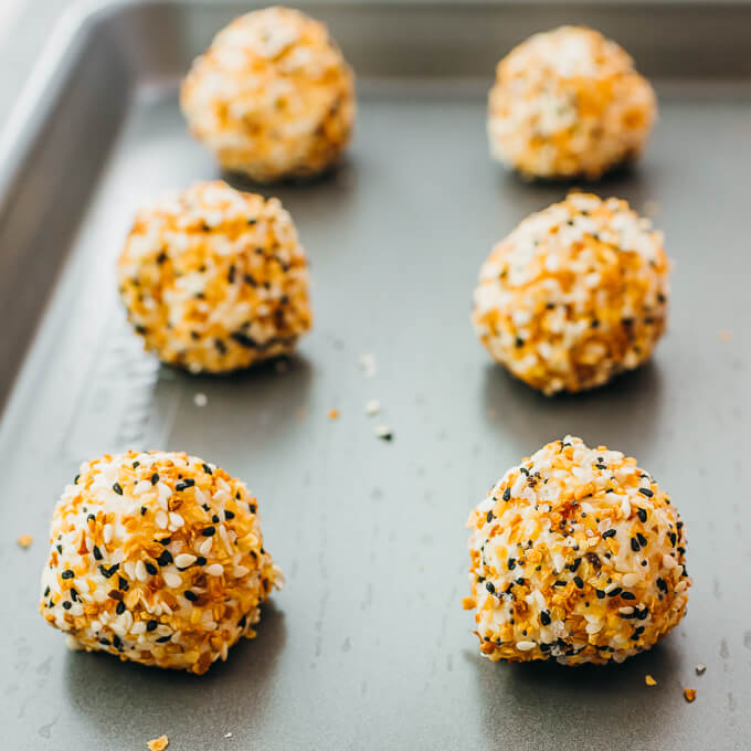 cheese balls covered in bagel seasoning on a sheet pan