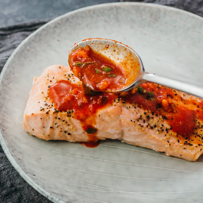 spooning chili lime sauce over cooked salmon