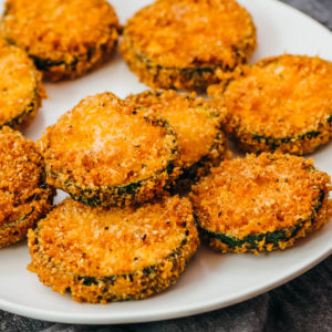 fried zucchini slices served on white plate