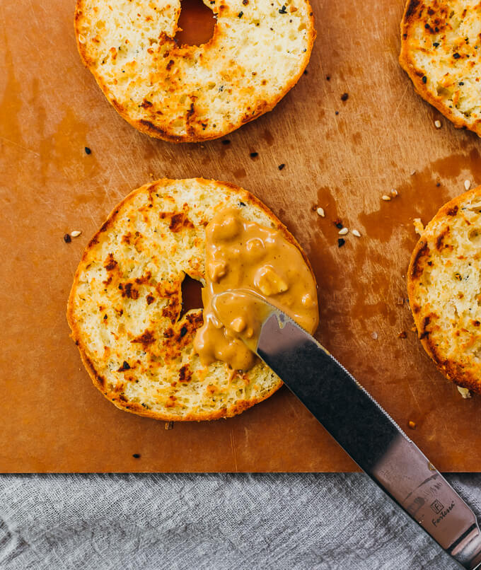 spreading peanut butter on sliced keto bagel