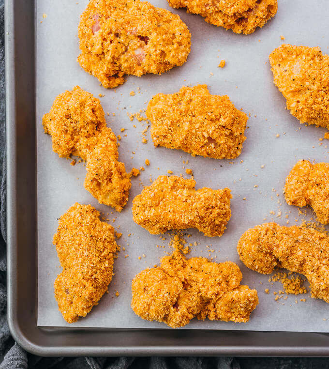 breaded chicken set aside on parchment paper