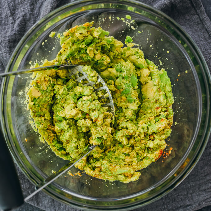 mashing avocado with seasonings