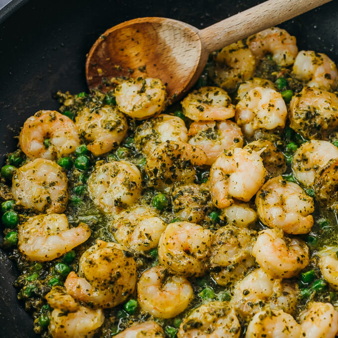 stirring pesto shrimp in skillet