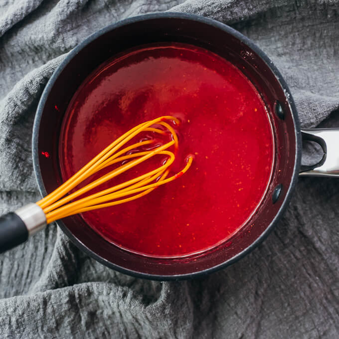 whisking raspberry mixture in saucepan