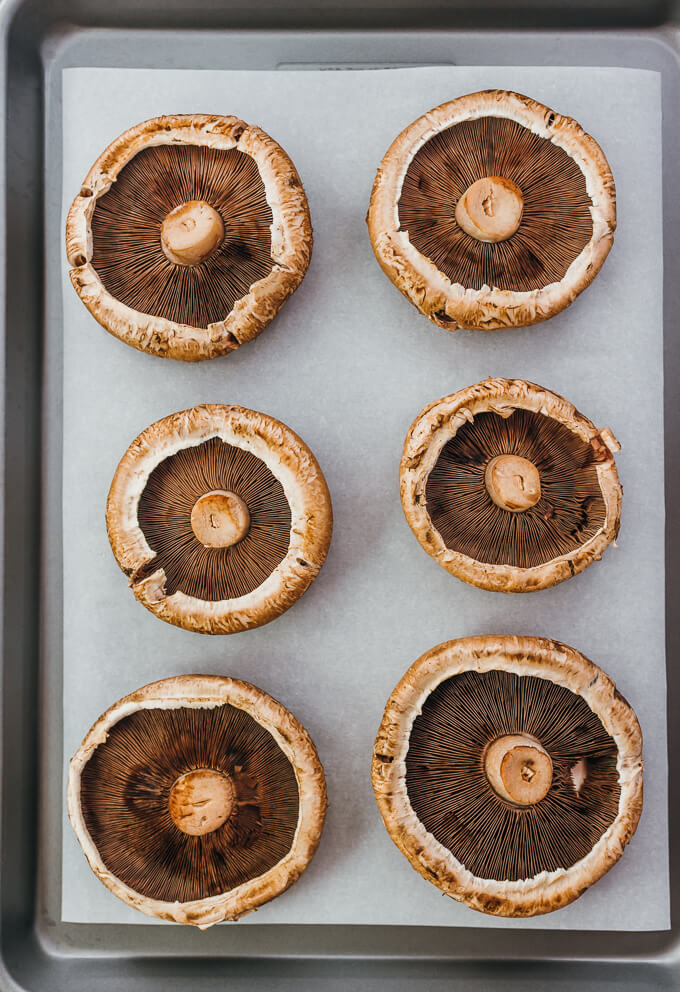 raw portobello mushroom caps on baking sheet