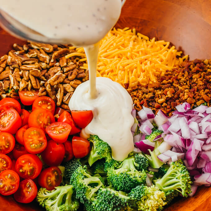 pouring dressing over broccoli salad