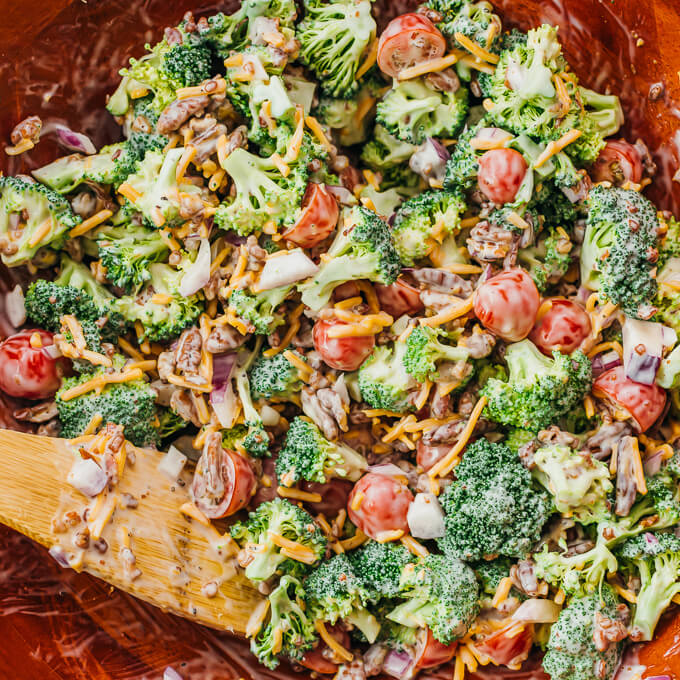 stirring broccoli salad with dressing