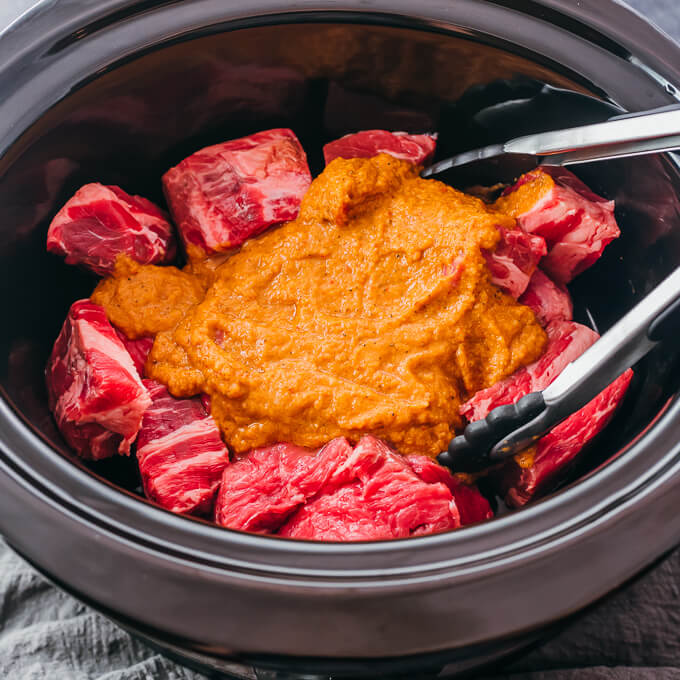 orange sauce over raw beef chunks