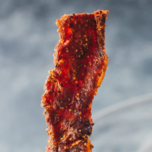 holding up single piece of beef jerky