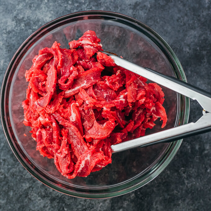 thinly sliced flank steak in bowl with spices