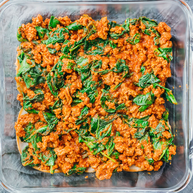 meat and spinach sauce in baking dish